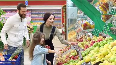 有一个小女儿的年轻父母在一家<strong>大型超市</strong>里选择新鲜的苹果。